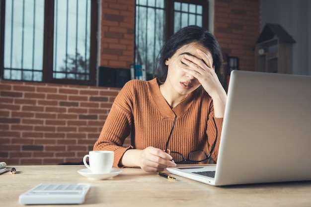 オフィスのコンピューターで働く悲しい女性