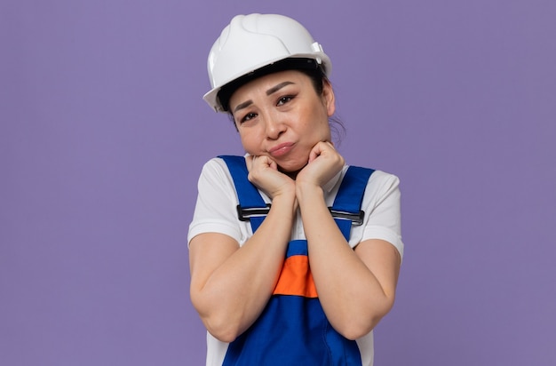 Sad young asian builder woman with white safety helmet putting hands on her face and looking 