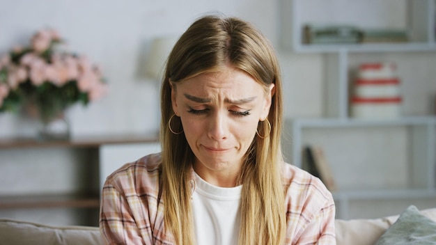 sad young woman crying on the sofa at home