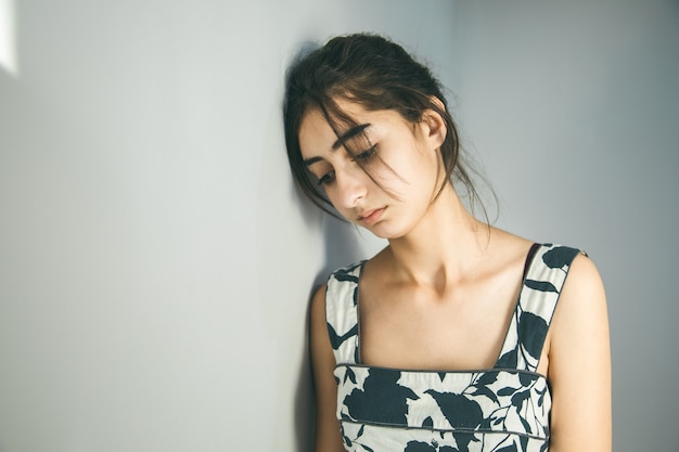 Sad young woman on grey wall