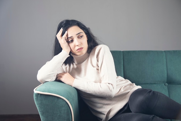 Sad young woman sitting on the sofa