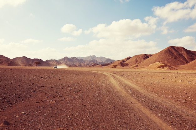 サファリとアフリカの極端な旅行。オフロード車の遠征で道路からほこりのある干ばつ山の風景。