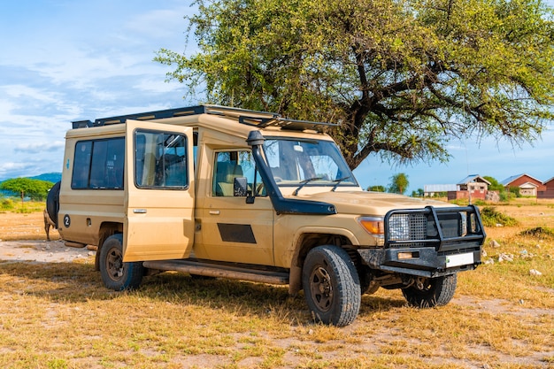 Safari-jeep die over een drukke onverharde weg rijdt op de vloer van de Ngorongoro-krater, op zoek naar activiteiten in het wild van dichtbij. Savannelandschap. Steile kanten van de krater in de verte. Uitgestorven vulkaan.Tanzania, Afrika