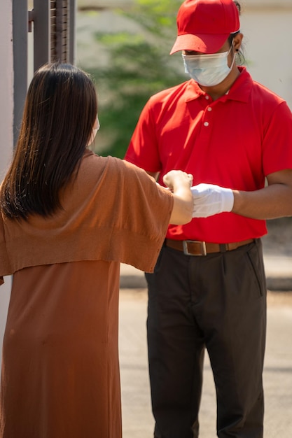 The safe delivery concept A courier in a red uniform with protective delivery goods