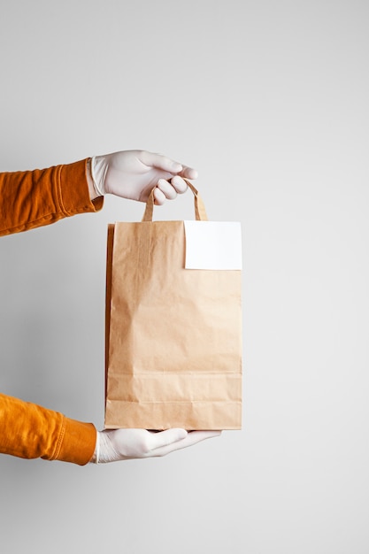 Consegna sicura dell'alimento in un sacchetto del mestiere e fattorino della pizza a casa su un fondo bianco
