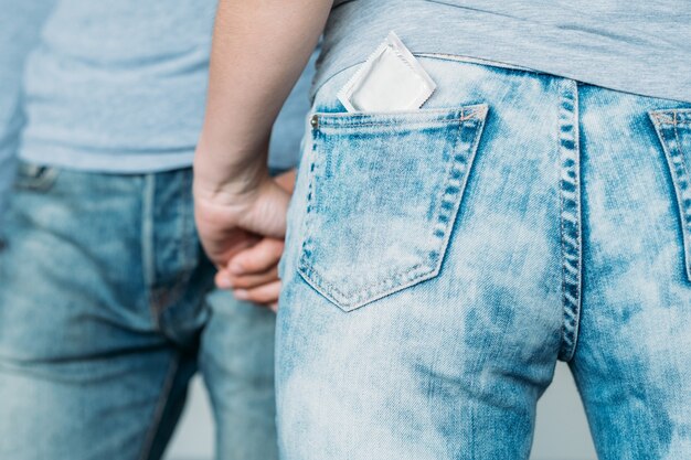 Amore sicuro e concetto di salute. protezione del preservativo da hiv e aids. backview di una donna con un contraccettivo nella tasca dei jeans