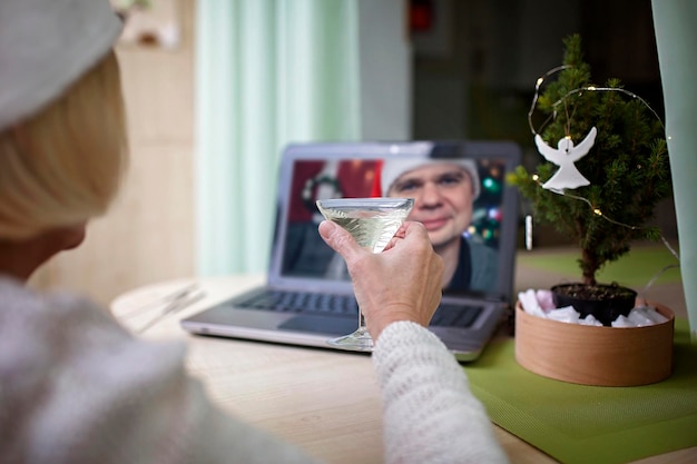 Фото Безопасное онлайн празднование пожилая женщина с бокалом вина и празднует рождество виртуально