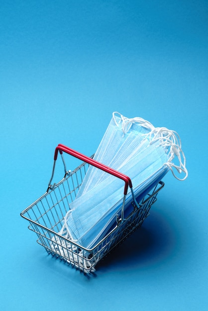 검역 개념에 안전하고 온라인 쇼핑. 파란색 배경 위에 보호 의료 마스크 쇼핑 바구니