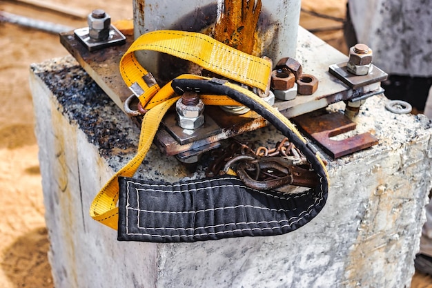 The safety belt of a welder or assembler lies on a concrete\
foundation at a construction site protection of a person working at\
height safety engineering