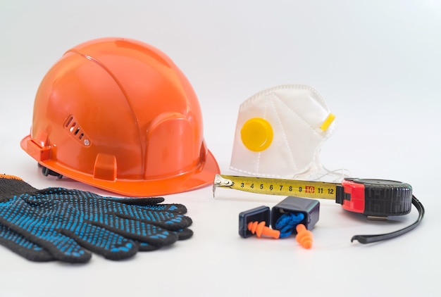 Safety equipment with helmet, respirator, ear plugs and gloves isolated on white. Means of protection for a large industrial enterprise.