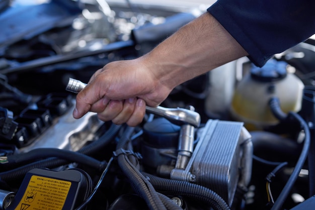 Safety first High angle shot of an unrecognizable male mechanic working on the engine of a car during a service