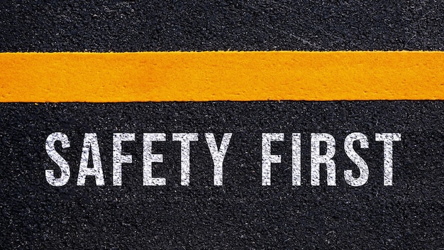 写真 アスファルト道路の真ん中の道路に書かれた安全第一のテキストと黄色の線 通りの安全第一の言葉