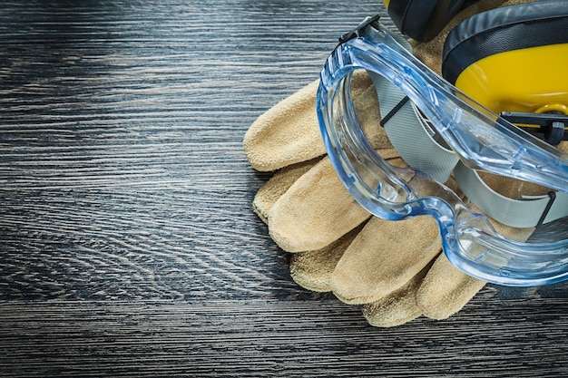 Safety glasses gloves earmuffs on wooden board