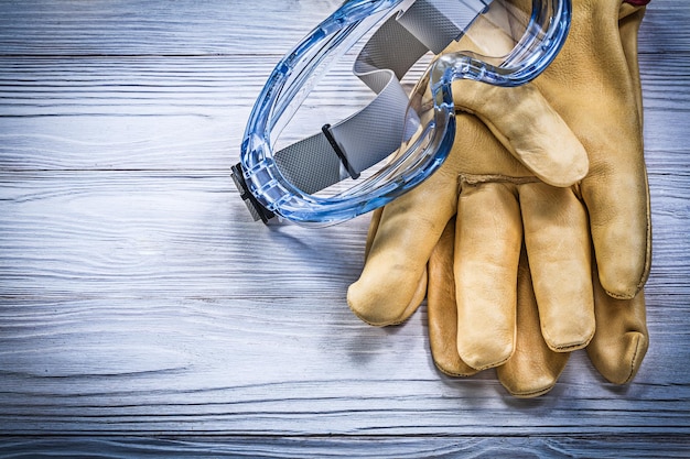 Safety glasses leather gloves on wooden board construction concept