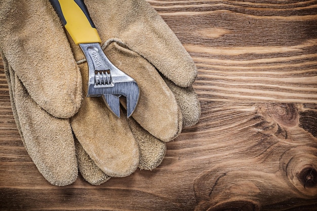 Safety gloves adjustable wrench on wooden board construction concept