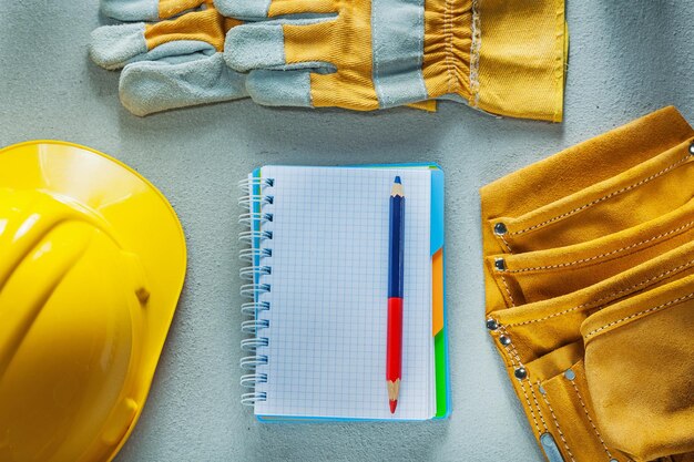 Защитные перчатки строительный шлем ноутбук карандаш инструмент лента измерительная лента на бетонном фоне.