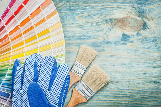 Safety gloves color sampler paint brushes on wooden board construction concept