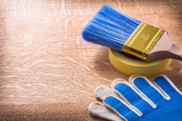 Safety gloves paint brush and duct tape on wooden board maintenance concept