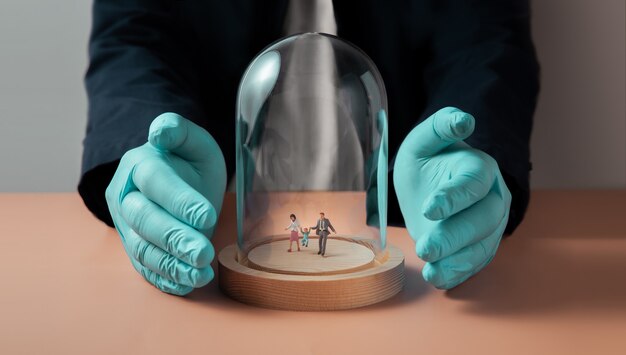 Photo safety and health insurance during coronavirus concept. miniature figure of family walking inside a glass dome cover