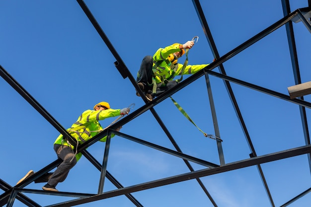 Apparecchiature di altezza di sicurezza in cantiere; il lavoratore asiatico indossa l'attrezzatura di altezza di sicurezza per installare il tetto. dispositivo anticaduta per lavoratore con ganci per imbracatura di sicurezza.