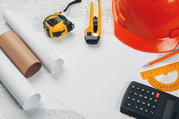 safety helmet and Scrolls of engineering drawings and supplies