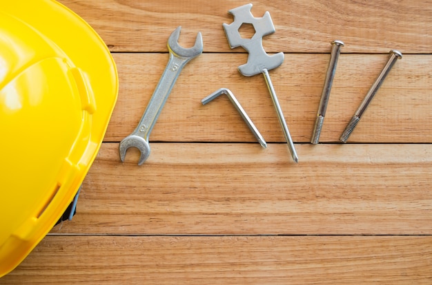 Safety helmet and tools on wooden board from top view