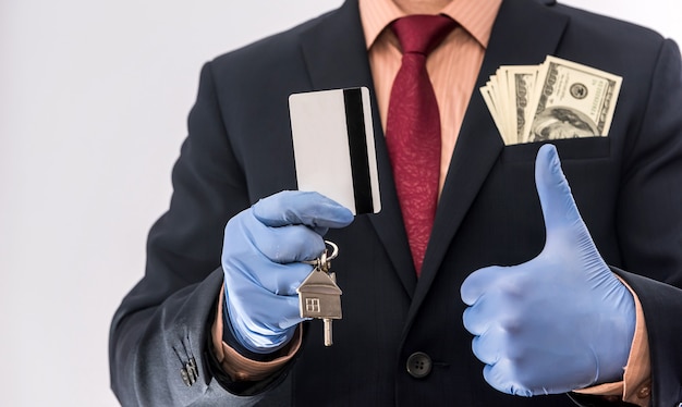 Safety sale or rent house man in medical gloves hold house key and dollar