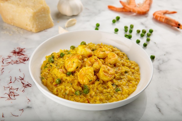 SAFFRAAN RISOTTO MET GARNALEN geserveerd in een schotel geïsoleerd op een grijze achtergrond zijaanzicht