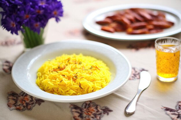 Foto fiori di zafferano accanto a un piatto finito di risotto alla milanese