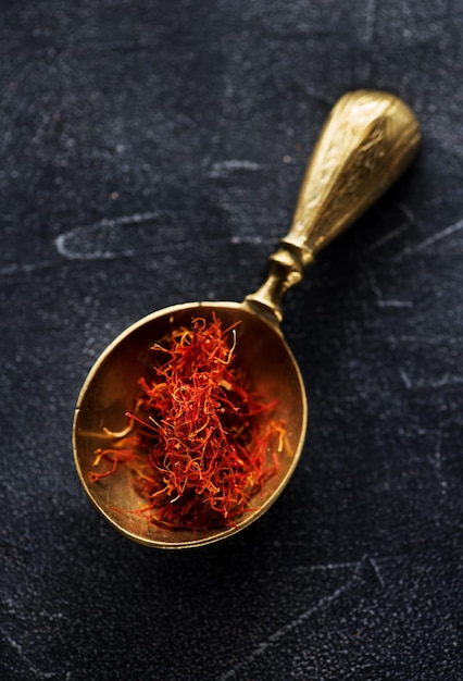 Saffron Spice. Saffron spices in a brass spoon. Indian spice top view. Seasonings, condiments. Cooking ingredients, flavor