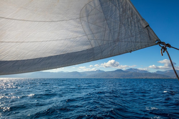 Sail boat with set up sails gliding in open sea near islands\
greece