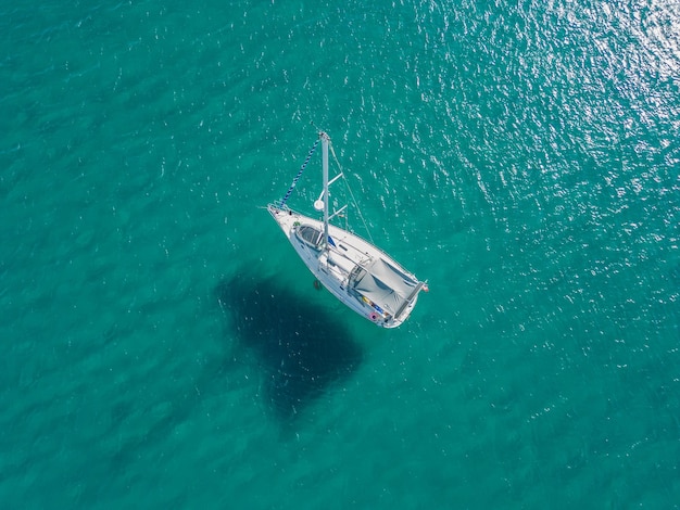 Sailboat anchored in shallow water and shadows on sandbank. Colorful turquoise water. Top view.