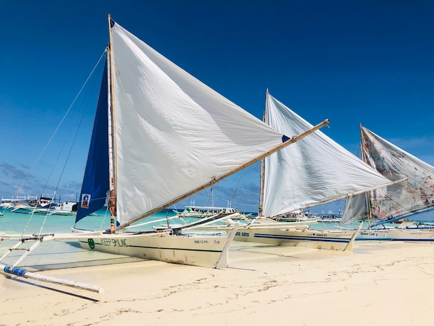 Foto barca a vela sulla spiaggia contro il cielo blu