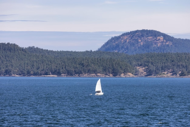 Sailboat in canadian landscape by the ocean and mountains