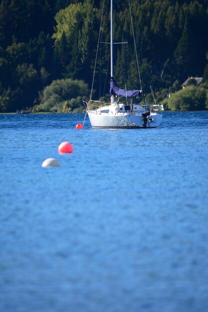 青い水の湖の真ん中にある帆船