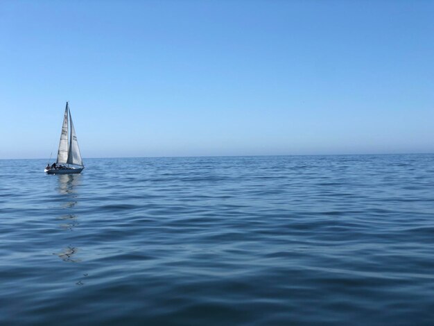 Фото Парусная лодка плывет по морю на чистом небе.