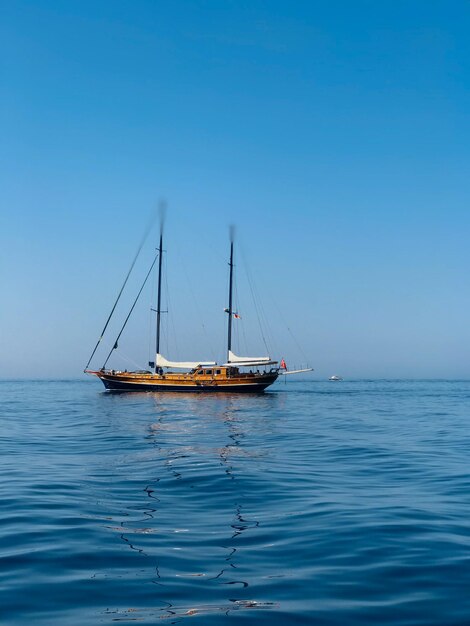 Sailboat sailing on sea against clear blue sky