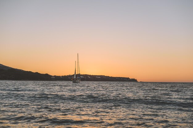 Photo sailboat sailing on sea against clear sky during sunset