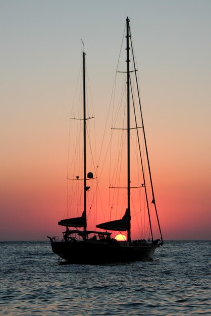 Foto barca a vela che naviga sul mare contro il cielo durante il tramonto