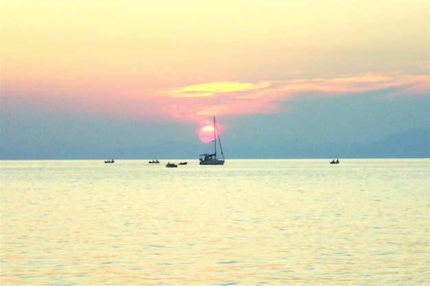 Una barca a vela che naviga in mare al tramonto