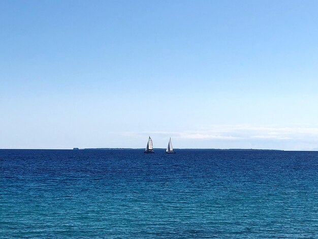 Sailboat in sea against blue sky