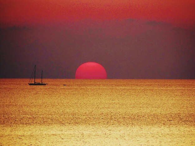 Foto barca a vela sul mare contro il cielo durante il tramonto