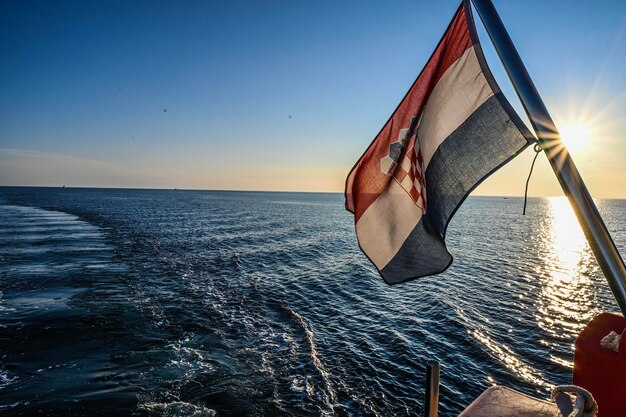 Sailboat in sea against sky during sunset