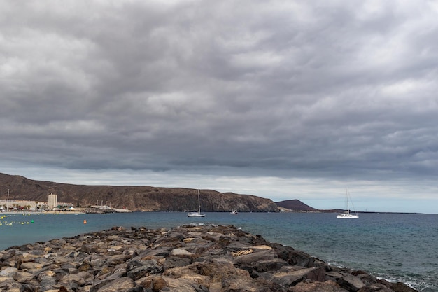 Photo a sailboat sits on the rocks in the water.