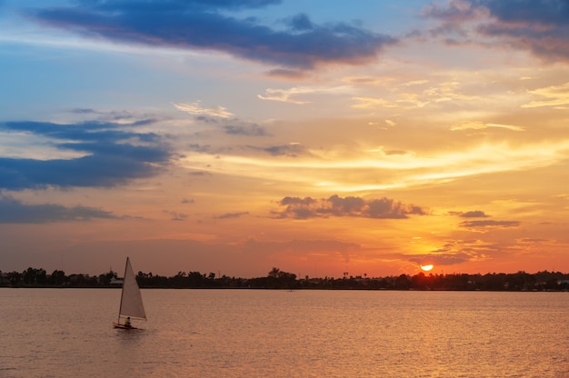 sailboat in water with sunset scene of colorful sky