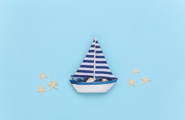 Sailboat with starfish on a blue background. Travel minimalism concept. Top view. Flat lay