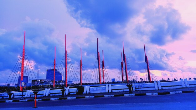 Sailboats on bridge against sky at sunset