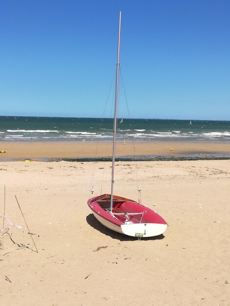 Sailboats moored on beach against clear sky