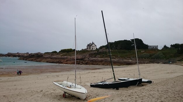 Foto barche a vela ormeggiate sulla spiaggia contro il cielo