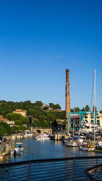 Sailboats moored at harbor against clear blue sky